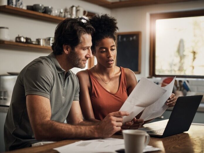 When did this happen. Cropped shot of an affectionate young couple going through paperwork while doing their budget at home.