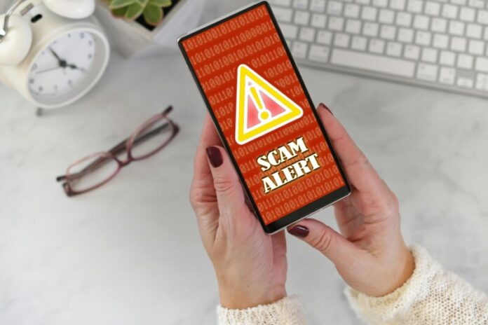 female-holding-a-phone-at-desk-with-scam-alert-war-2022-11-14-04-18-33-utc
